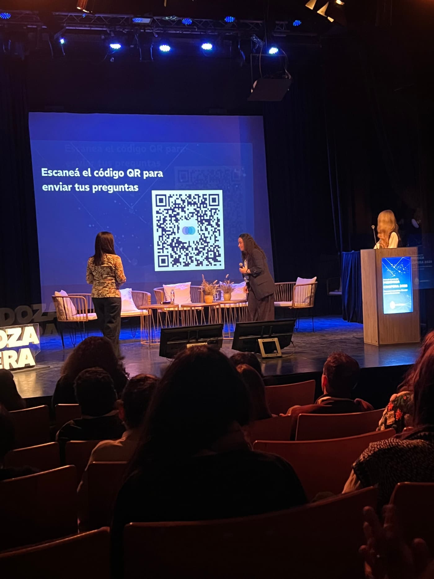 Pantalla del escenario con un código QR gigante y el texto Escaneá el código QR para enviar tus preguntas, durante un panel